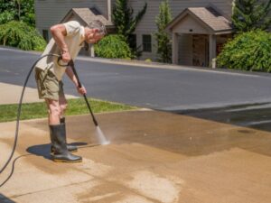 A man cleaning a concrete driveway.